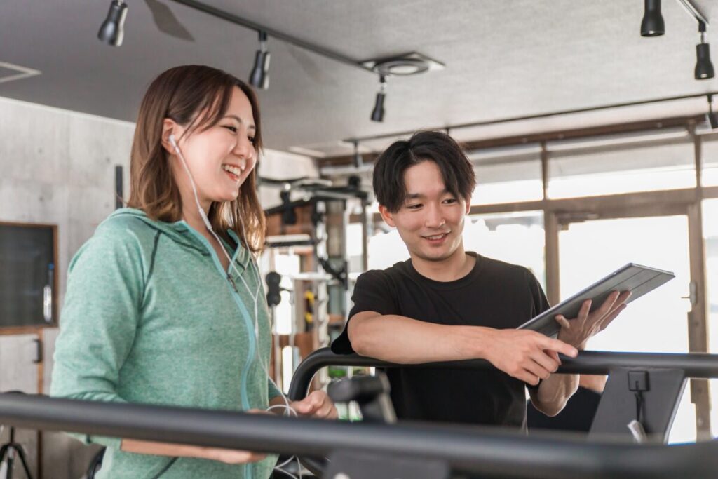 トレーナーとジムで運動する女性